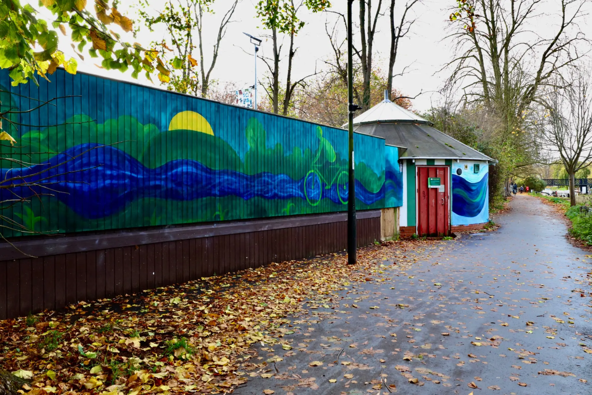 The Human Current mural extending along the pathway at Jesus Green Lido